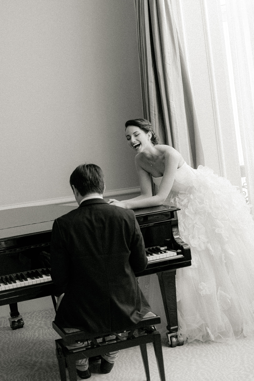 Bride laughing beside piano in Plaza Athénée suite